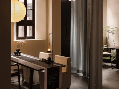 A modern restaurant interior with concrete floors, a long dining table, and minimalist decor.