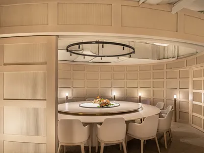 A minimalist restaurant interior with a round table and white chairs.