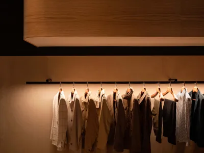 一排木質衣架展示各式服裝，搭配溫暖燈光照明。