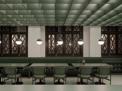 Industrial-style restaurant interior with green leather seating and white pendant lights.
