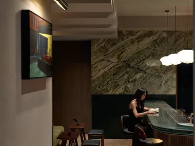 A modern bar with black marble countertops and black stools.