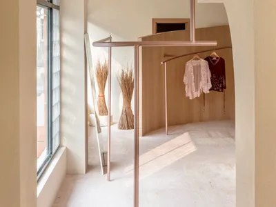 A fashion retail store displaying clothing on metallic hangers against a wooden background.
