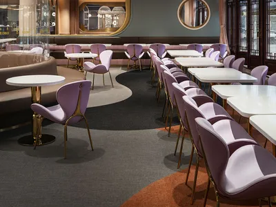 A modern café interior featuring metallic furniture and tiled flooring.
