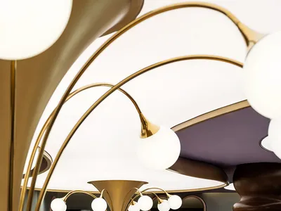 A modern restaurant interior featuring gold glass elements, metallic accents, and fabric seating