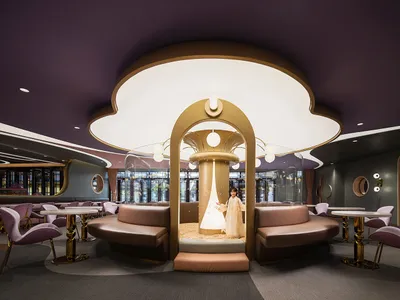 Modern cafe interior with leather seating, glass tables, and metal accents.