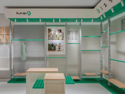 A contemporary retail store features metal perforated walls and wooden tables, showcasing modern design elements.