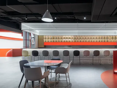 A modern bar interior with red accent walls, white concrete surfaces, and metal stools.