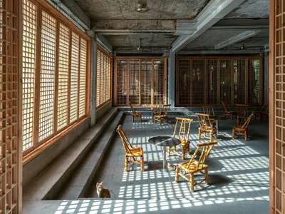 Industrial restaurant interior with concrete ceiling, wooden walls, and glazed windows.