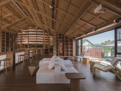A restaurant with industrial design features, wooden furniture, and exposed beams on the ceiling.