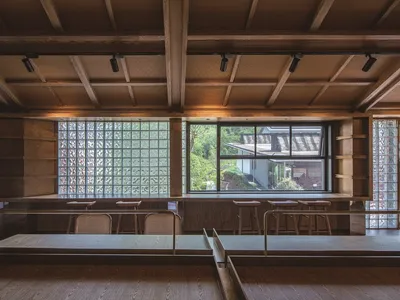 Industrial-style restaurant interior with wooden materials and large windows.
