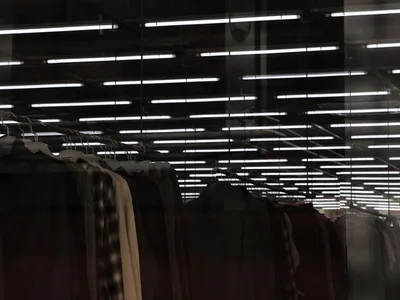 服裝吊掛在衣架上，置於玻璃牆面零售展示區