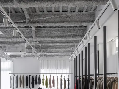 現代服裝零售店展示極簡設計，搭配金屬衣架、玻璃牆面與混凝土地板。
