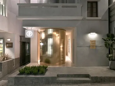 The entrance to a modern hotel, featuring glass walls and concrete flooring.