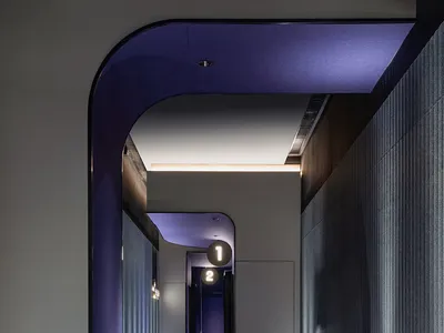 一張現代酒店走廊的室內攝影，展現極簡設計元素，如乙烯基地板與混凝土柱