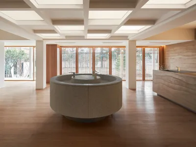 Modern hotel lobby with natural stone flooring and a circular central feature.