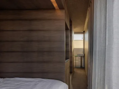A minimalist bedroom with wooden panels on the wall and ceiling.