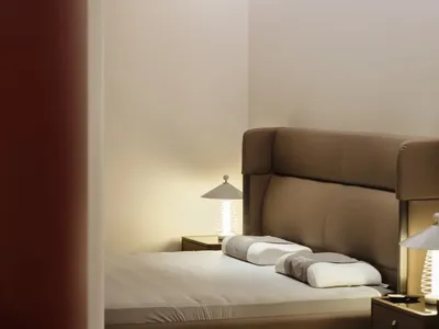 A minimalist bedroom with concrete walls and a large bed.