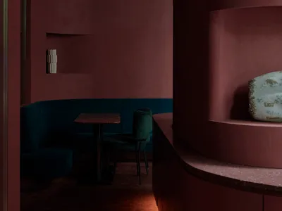 Contemporary restaurant with dark blue velvet seating and marble table surface.