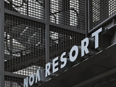 一面工業風金屬牆飾，上面刻有「Noa Resort」字樣。