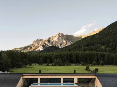 Modern hotel room with black wood walls and a glass area overlooking mountains
