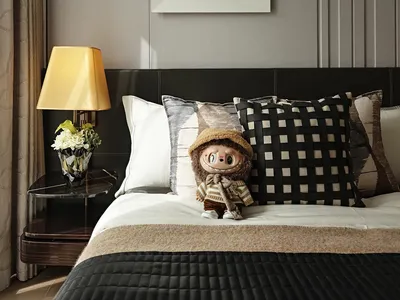 Bedroom with modern brown leather headboard, white and brown bedding, and decorative pillows.