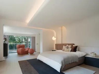 A modern minimalist bedroom with a neutral color palette featuring a large bed, plush pillows, and a sleek design.