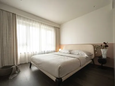 現代臥室以灰褐色與木質布面床為主，搭配簡約設計、白窗簾，以及花瓶插花