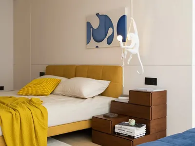 Modern minimalist bedroom featuring a yellow upholstered bed, wooden nightstands, and a creative hanging monkey light fixture
