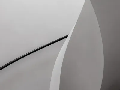 Curved white concrete stairs with a black handrail in a modern interior space.