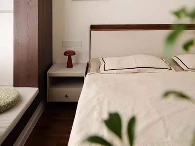 A modern minimalist bedroom featuring a headboard with a wooden frame and a white bedspread.