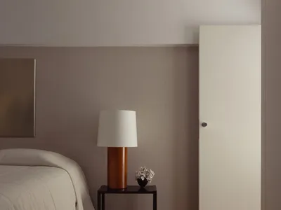 Modern minimalist bedroom featuring wooden furniture with a white lamp and vase.