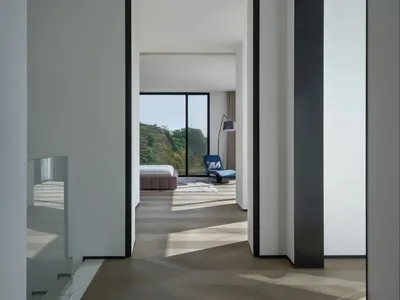 A minimalist bedroom with a wooden floor and a bed.