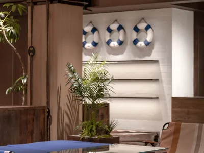 Industrial-style living room featuring wooden furniture and a glass-top coffee table, with a plant and a lifebuoy decoration.