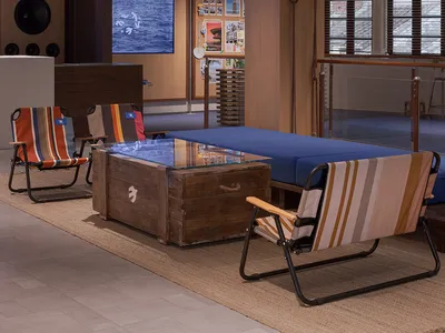 An industrial-style reception lounge with a textured canvas ceiling, wooden floor, and glass coffee table.