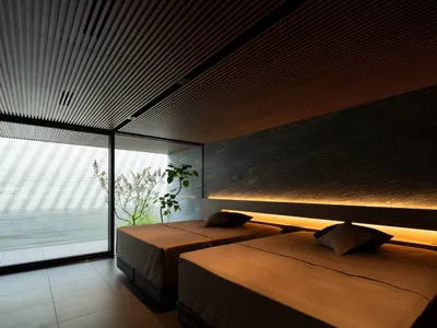 Modern, minimalist hotel room with concrete and marble finishes and two single beds.
