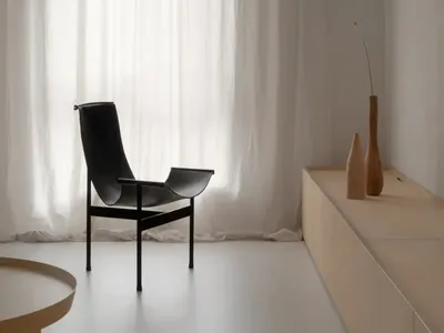 A minimalist bedroom with neutral materials and a large window.