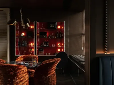 Modern bar interior featuring red acrylic walls and metallic finishes.
