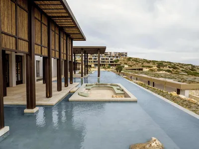 Modern hotel lobby with concrete pool and seating area.