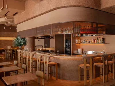 Modern restaurant bar with tiled walls, marble countertops, and concrete bar stools.