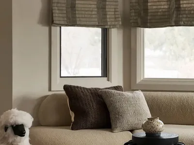 Comfortable beige sofa with dark brown textured cushions and a plush white sheep figurine in a cozy living room setting.