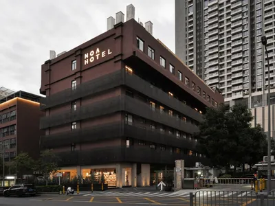 一座擁有磚牆外觀的現代旅館建築，搭配燈光照亮的招牌。