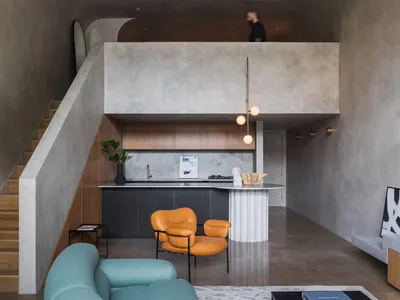 Modern living room and kitchen with open-plan design, featuring concrete texture walls and floors.
