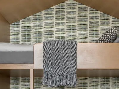 Modern bunk bed with a geometric floor pattern, wooden ladder, and plush bedding in a bedroom setting.