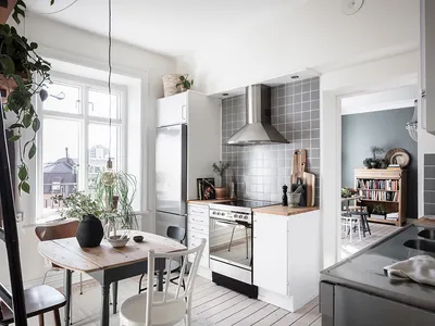 A modern, minimalist kitchen featuring white cabinetry, stainless steel appliances, and a white wooden floor.