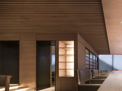 A sleek, modern restaurant bar with wooden accents, minimal lighting, and a spacious seating area.