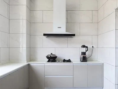 Modern minimalist kitchen with white marble countertops and backsplash, featuring sleek cabinets and stainless steel applianc