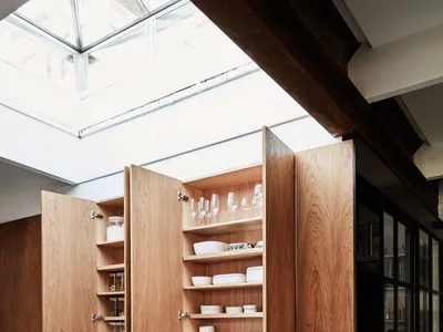現代廚房內的木質收納櫃，展示著碗盤、玻璃杯與其他廚具。