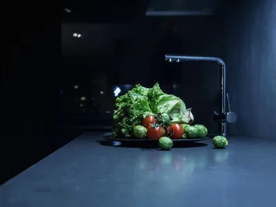 一間廚房場景，配有混凝土檯面及一盤蔬菜。