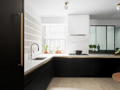 A modern kitchen with marble countertops and glass cabinets, featuring black cabinetry and a wooden dining table.