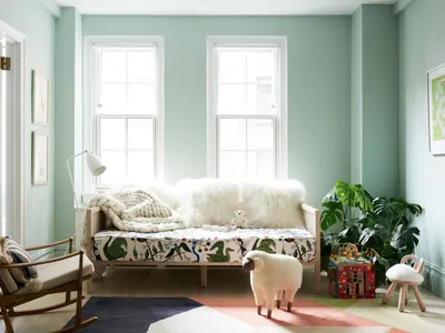 A children's bedroom featuring textiles, cushions, plants, and a wooden frame